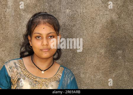 Ritratto di una bella giovane ragazza adolescente, di nazionalità indiana. Sullo sfondo della parete a trama con spazio di copia per testo o parola. All'aperto Foto Stock