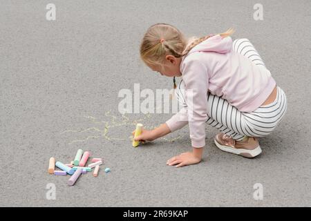 Piccolo bambino che disegnano il sole con gesso su asfalto Foto Stock