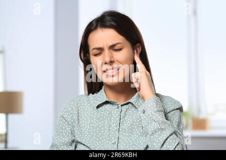 Giovane donna che soffre di dolore all'orecchio all'interno Foto Stock