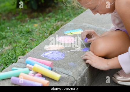 Bambino piccolo disegno palloncini e bandiera ucraina con gesso sul marciapiede all'aperto, primo piano Foto Stock