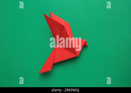 Bellissimo uccello rosso origami su sfondo verde, vista dall'alto Foto Stock