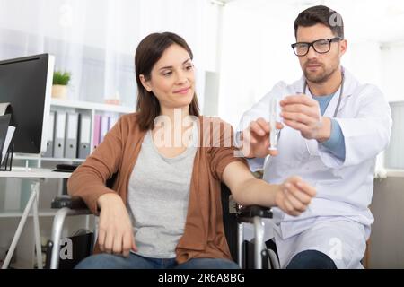 donna disabile che riceve il vaccino in clinica Foto Stock