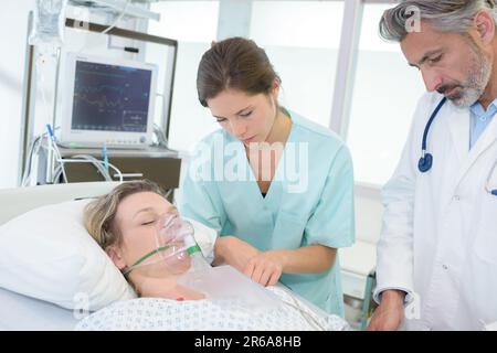 paziente che indossa una maschera per ossigeno sdraiato sul letto in ospedale Foto Stock