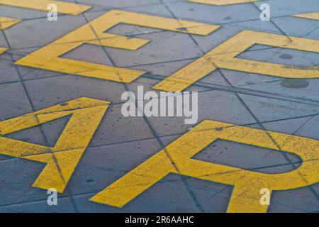 Tenere il cartello trasparente con le lettere grafiche gialle sul fondo stradale, Melbourne Australia. Foto Stock