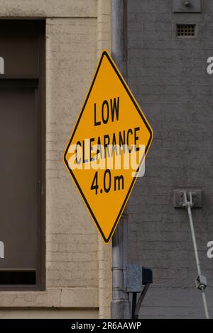 Cartello australiano a bassa distanza che mostra le informazioni per gli utenti della strada, carattere nero su sfondo giallo metallico. Foto Stock