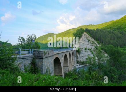 Vecchio ponte sul fiume Enza a Neviano degli Arduini, Parma, Emilia Romagna, Italia durante il tramonto sulle montagne Foto Stock