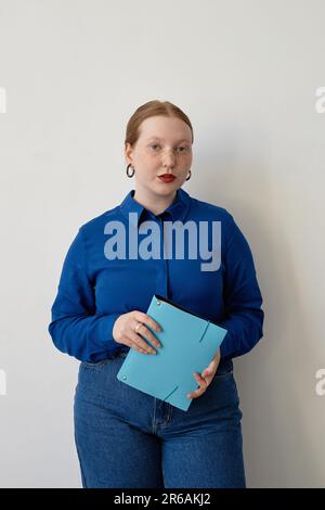 Ritratto verticale di giovane donna con capelli rossi che indossa un abito casual business di colore blu brillante Foto Stock