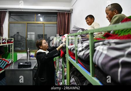 (230608) -- TINGRI, 8 giugno 2023 (Xinhua) -- Un insegnante si prende cura degli allievi nel dormitorio di una scuola elementare del comune di Zhaxizom nella contea di Tingri, città di Xigaze, regione autonoma del Tibet del sud-ovest della Cina, 5 giugno 2023. La scuola elementare di Zhaxizom Township è la scuola più vicina al Monte Qomolangma, con una distanza di poco più di 40 chilometri. Per soddisfare le diverse esigenze degli studenti, la scuola ha istituito classi di interesse come pianoforte, informatica, arte, trasmissione, sport, danza e artigianato. Attualmente, la scuola elementare ha un solo pianoforte. Quindi, eleggere Foto Stock