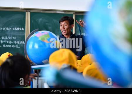 (230608) -- TINGRI, 8 giugno 2023 (Xinhua) -- Damba Rinqen, vice presidente di una scuola elementare di Zhaxizom Township, istruisce gli studenti in una classe di scienza nella contea di Tingri, Xigaze City, regione autonoma del Tibet del sud-ovest della Cina, 5 giugno 2023. La scuola elementare di Zhaxizom Township è la scuola più vicina al Monte Qomolangma, con una distanza di poco più di 40 chilometri. Per soddisfare le diverse esigenze degli studenti, la scuola ha istituito classi di interesse come pianoforte, informatica, arte, trasmissione, sport, danza e artigianato. Attualmente, la scuola elementare ha un solo pianoforte. Foto Stock