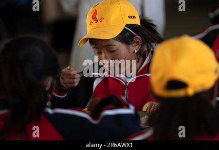 (230608) -- TINGRI, 8 giugno 2023 (Xinhua) -- gli studenti pranzano nella mensa di una scuola elementare del comune di Zhaxizom nella contea di Tingri, Xigaze City, regione autonoma del Tibet nel sud-ovest della Cina, 5 giugno 2023. La scuola elementare di Zhaxizom Township è la scuola più vicina al Monte Qomolangma, con una distanza di poco più di 40 chilometri. Per soddisfare le diverse esigenze degli studenti, la scuola ha istituito classi di interesse come pianoforte, informatica, arte, trasmissione, sport, danza e artigianato. Attualmente, la scuola elementare ha un solo pianoforte. Pertanto, le tastiere elettroniche sono Foto Stock