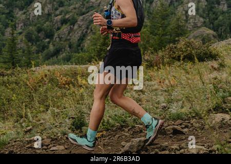 runner femminile che corre in montagna, gara maratona del sentiero estivo Foto Stock