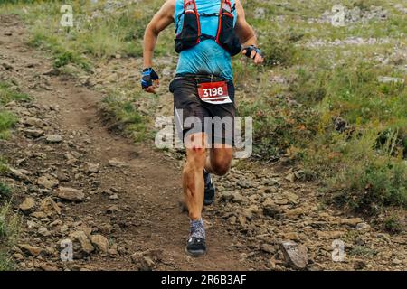 atleta runner discesa montagna in pista maratona corsa, ginocchio nel sangue dopo la caduta Foto Stock