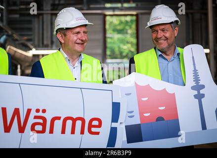 08 giugno 2023, Schleswig-Holstein, Wedel: Robert Habeck (Bündnis 90/Die Grünen, r), ministro federale dell'economia e della protezione del clima, e Jens Kerstan (Bündnis 90/Die Grünen), senatore per l'ambiente, il clima, l'energia e l'agricoltura ad Amburgo, In occasione di un evento stampa, tenere i cartelli con il testo 'Wärme' ('heat') e le sagome della sala concerti e della torre della televisione di Elbphilharmonie per segnare il completamento di un impianto eolico-termico (power-to-heat) sul sito della centrale combinata di Wedel. Il nuovo impianto di riscaldamento, che converte l'energia eolica in teleriscaldamento verde, funziona sulla p Foto Stock