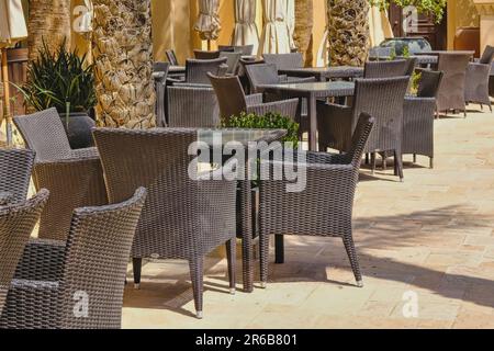 Bar all'aperto vuoto con poltrone e tavoli in rattan. Sedie in vimini all'aperto sulla terrazza della caffetteria. Arredamento urbano moderno ed ecologico Foto Stock