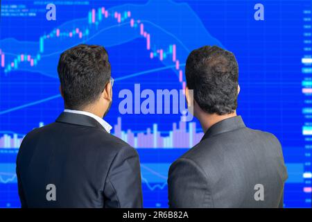 Due commercianti di mercato azionario guarda lo schermo mostra la grafica del grafico dei candelabri scendendo, il crollo del mercato finanziario. Crypto e forex trading. Foto Stock