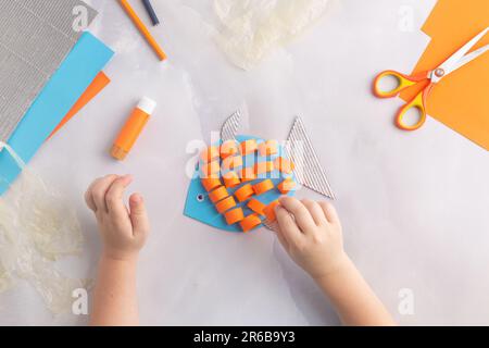 Carta adorabile pesce con i bambini a casa. Mani fare il fai da te estate crafting. Giornata dell'oceano. Foto Stock