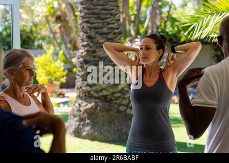 Ha messo a fuoco diversi anziani che esercitano in classe pilates con l'allenatore femminile Foto Stock