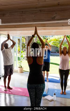 Ha messo a fuoco diversi anziani che esercitano in classe pilates con l'allenatore femminile Foto Stock