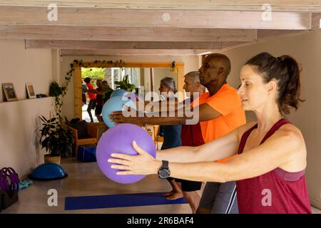 Ha messo a fuoco gli anziani diversi usando le sfere di esercitazione nella classe dei pilates con l'allenatore femminile Foto Stock