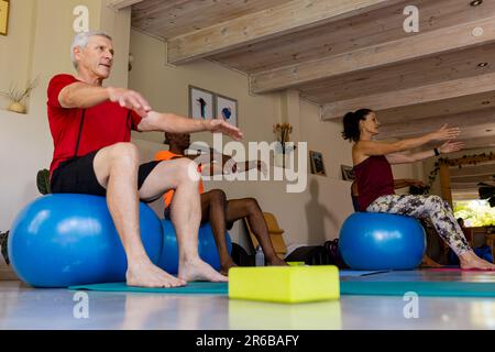 Ha messo a fuoco gli anziani diversi usando le sfere di esercitazione nella classe dei pilates con l'allenatore femminile Foto Stock