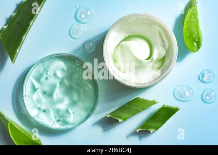 Aloe vera foglie di pianta e gel cosmetico per la cura della pelle su sfondo blu, vista dall'alto. Gel cosmetico naturale all'aloe vera organica in capsula di Petri. Foto Stock