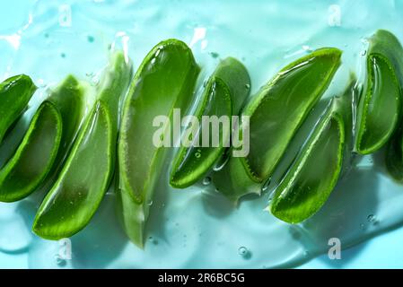 Aloe vera affetta foglie in gel per la cura della pelle su sfondo blu. Gel cosmetico naturale organico all'aloe vera. Foto Stock