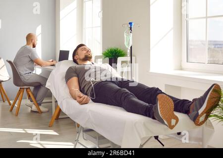 Paziente di sesso maschile che riceve infusione endovenosa in ufficio medico Foto Stock
