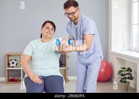 Fisioterapista aiutare paziente donna in sovrappeso durante la fisioterapia di riabilitazione muscolare Foto Stock