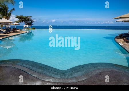 Zanzibar, Tanzania - 16 marzo 2023: Logo con una R per il Royal Zanzibar Resort, di fronte alla piscina a sfioro e l'Oceano Indiano Foto Stock