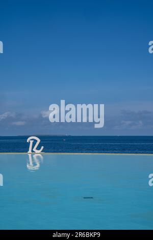 Zanzibar, Tanzania - 16 marzo 2023: Logo con una R per il Royal Zanzibar Resort, di fronte alla piscina a sfioro e l'Oceano Indiano Foto Stock