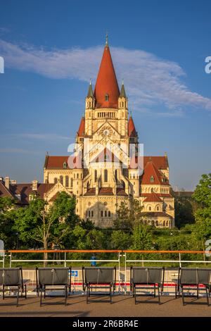 Sedie a sdraio sul ponte superiore con la chiesa di San Francesco d'Assisi sulla riva del Danubio, Vienna, Austria Foto Stock