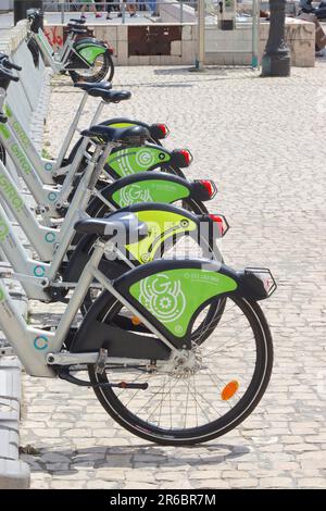 Le biciclette elettriche Fira si trovano in una fila quasi vuota in una delle piazze principali del Portogallo, a testimonianza della popolarità di questo modo di trasporto. Foto Stock