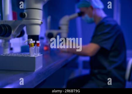 Operatore di laboratorio che esamina i campioni al microscopio in clinica Foto Stock