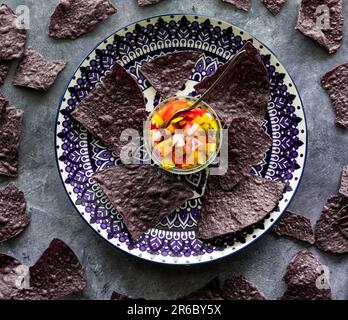 Tortilla di mais blu con una ciotola di salsa cunky fatta in casa. Foto Stock