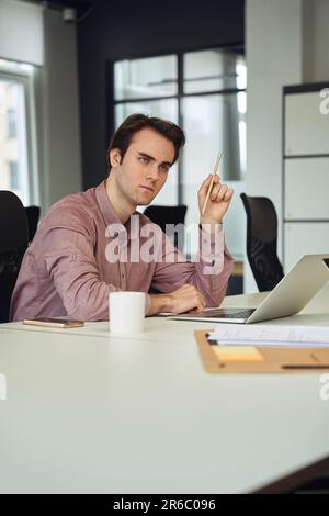 Un dipendente serio dell'azienda che medita sull'attività lavorativa nel suo posto di lavoro Foto Stock