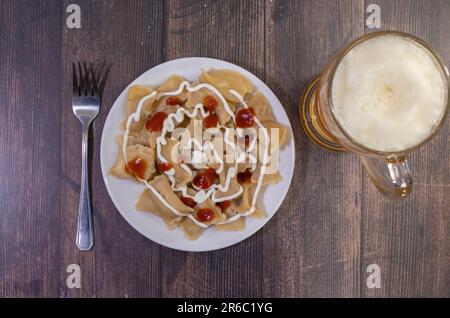 Deliziosa casa calda ceco tradizionale gulasch di manzo servita con cotti al vapore Gnocchi cechi o knedliky sulla piastra nera sul tavolo in legno con vetro di bee Foto Stock