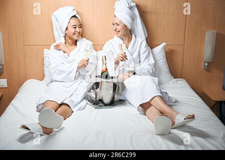 Due donne in accappatoi bevono champagne in camera Foto Stock