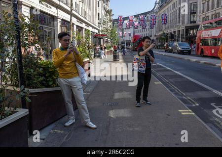 Turisti che scattano foto sui loro smartphone, Regent Street, West End di Londra in un caldo giorno estivo durante una mini-ondata di caldo nel giugno 2023, Londra, Regno Unito Foto Stock