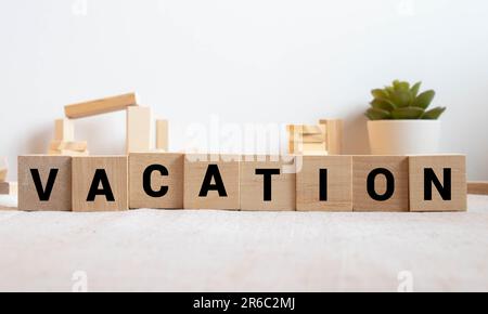 vacanza parola scritta in piccoli cubi di legno alfabeto su sfondo bianco isolato, concetto di viaggio. Foto Stock