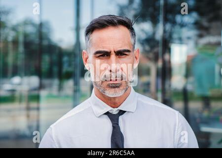 Primo piano individuale ritratto di serio uomo d'affari maturo guardando penoso fotocamera sul posto di lavoro. Un bel CEO aziendale maschile di successo in piedi con atteggiamento fiducioso e touthful. Illustrazione di alta qualità Foto Stock