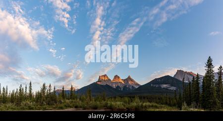 Vista panoramica a Canmore, Kananaskis durante l'estate con enormi cime montane in vista, torrente e foresta selvaggia. Foto Stock