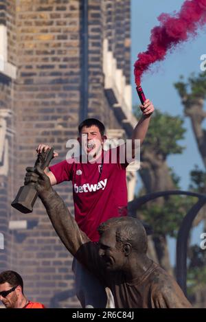 Newham, Londra, Regno Unito. 8th Giu, 2023. I giocatori e lo staff del West Ham United Football Club hanno festeggiato la vittoria del trofeo UEFA Europa Conference League con una parata di vittoria in autobus aperto attraverso il quartiere, dalla statua dei campioni vicino al vecchio stadio Boleyn Ground della squadra e terminando al Municipio di Stratford. La Statua rende omaggio agli ex giocatori della storia del club, anche dall’era della precedente vittoria della Coppa UEFA del 1965. I tifosi hanno tracciato la strada per festeggiare e rallegrarsi con la loro squadra. Fan su statua con bagliore Foto Stock