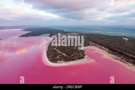 Lago rosa a Port Gregory in Australia Occidentale, acqua colorata da batteri e alghe, bel contrasto tra l'oceano blu e l'acqua rosa, nuvole Foto Stock