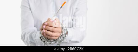 Le mani femminili legate con la siringa di insulina che tiene la catena Foto Stock