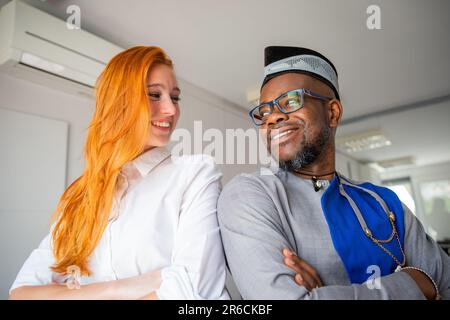 Due colleghi si guardano sorridendo in ufficio, uomini d'affari felici di culture diverse Foto Stock