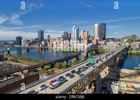 Skyline di Pittsburgh con il centro e il quartiere degli affari. Ponte dei treni e Ponte della libertà. Cielo blu chiaro sullo sfondo. Foto Stock