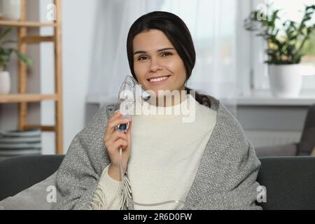 Giovane donna felice con nebulizzatore a casa Foto Stock