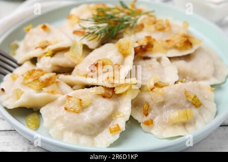 Gnocchi cotti (varenyky) con gustoso ripieno e cipolle fritte su piatto, primo piano Foto Stock