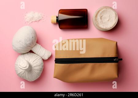 Preparazione per il centro benessere. Composizione a posa piatta con sacchetto per articoli da toeletta compatto e prodotti cosmetici su sfondo rosa Foto Stock