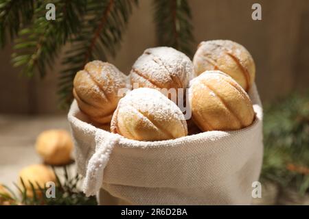 Deliziosi biscotti a forma di noci con zucchero a velo in sacco, primo piano Foto Stock